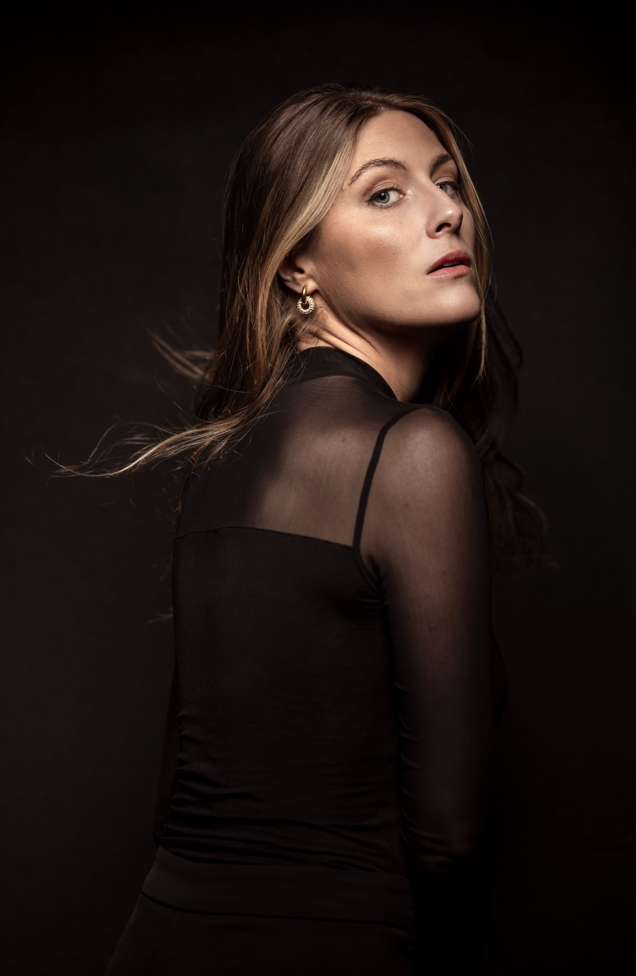 Ellinor Olmarken, portrait in black against a dark backdrop