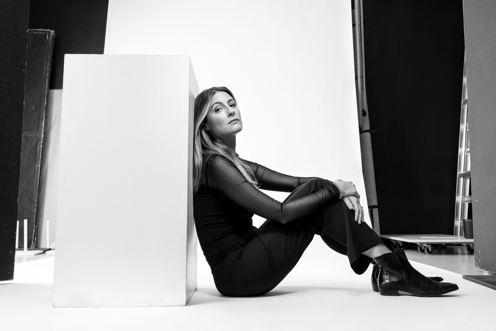 Ellinor Olmarken seated against a white plinth in the studio